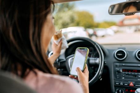 woman eating and texting while driving