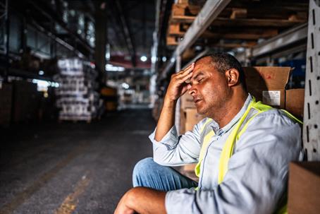 tired and sad man sitting in a warehouse