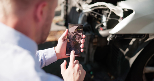 man taking photo of car accident scene