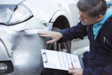 person inspecting damage to car
